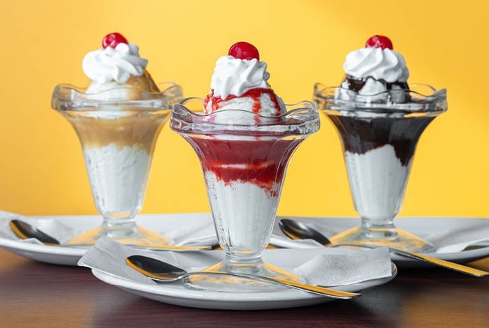 Three vanilla sundaes topped with Sugar cream sauce, strawberry, and chocolate sauce.