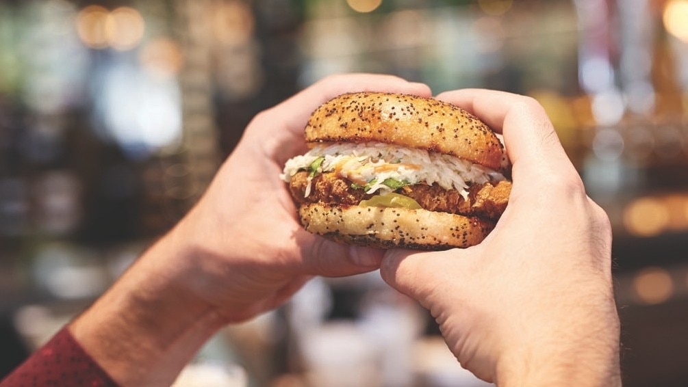 Hands holding a burger.