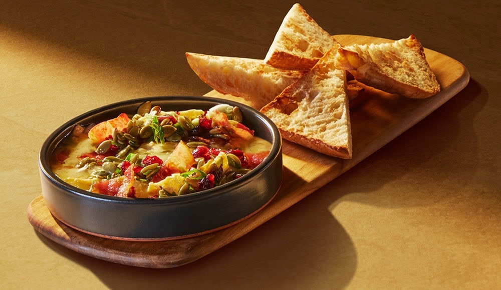 Melted La Sauvagine cheese dip with toasted ciabatta bread appetizer available in St-Hubert traditional rotisseries