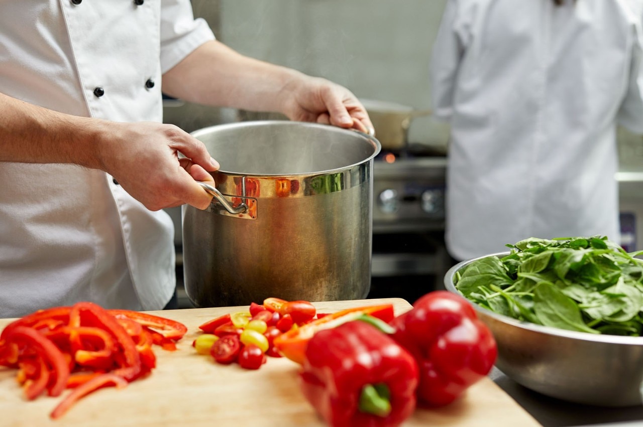 A chef in the kitchen with a pot