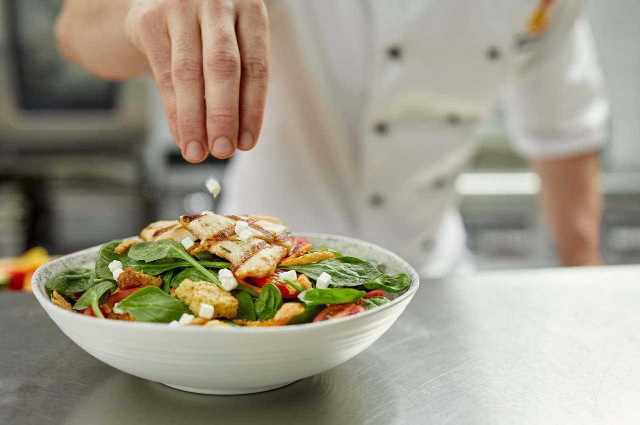 Cuisinier qui fait une salade pour illustrer les valeurs de santé et de qualité de St-Hubert