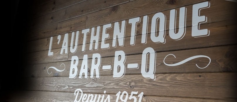 Inscription L'authentique Bar-B-Q sur le mur d'un restaurant St-Hubert pour illustrer nos classiques
