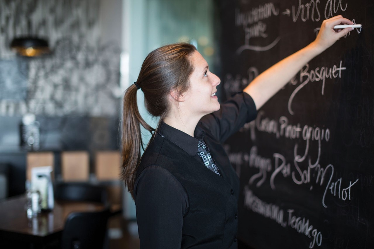 Serveuse qui écrit le menu à la craie sur l'ardoise St-Hubert