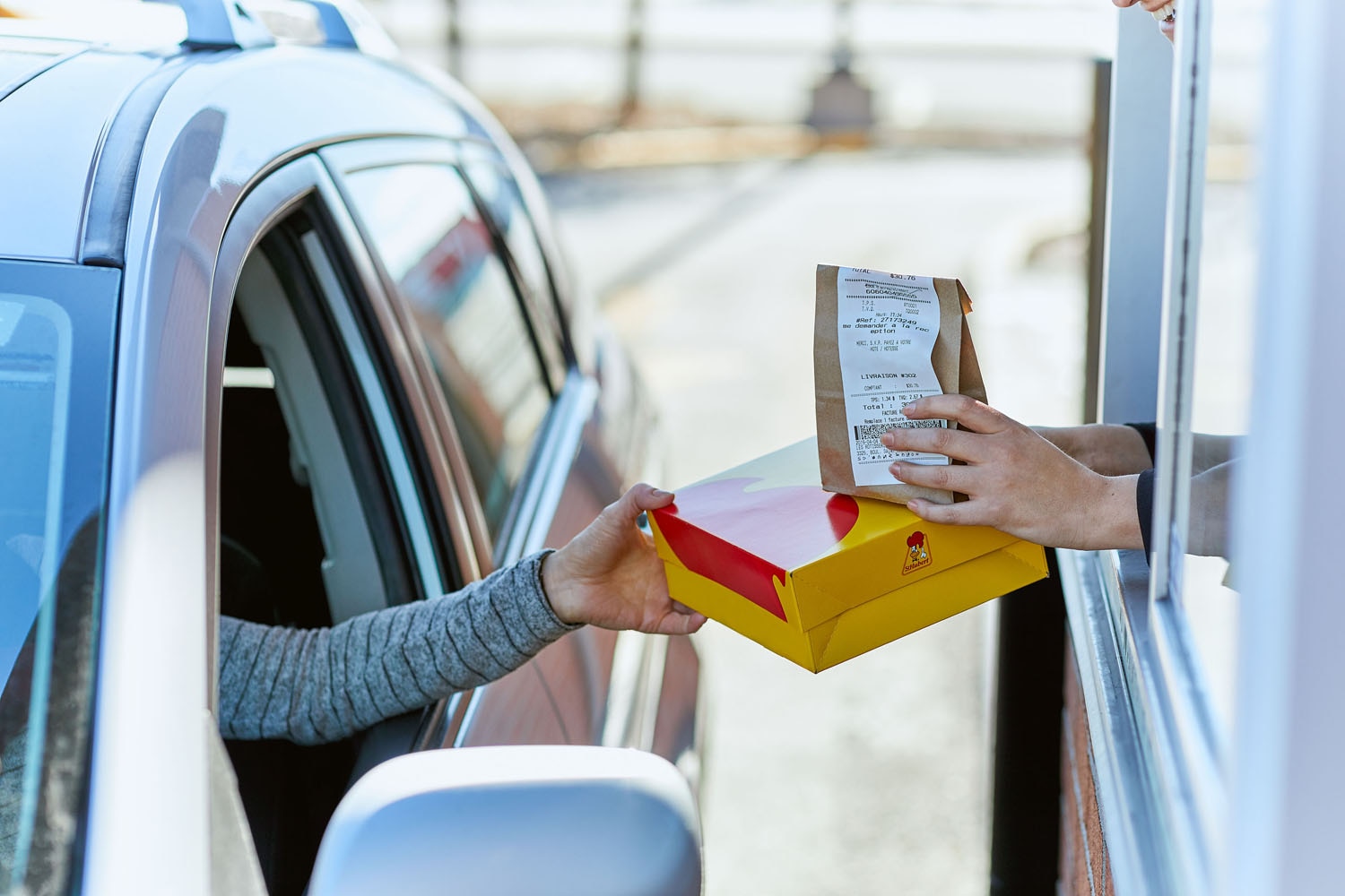 A customer getting his meal at a St-Hubert drive-thru