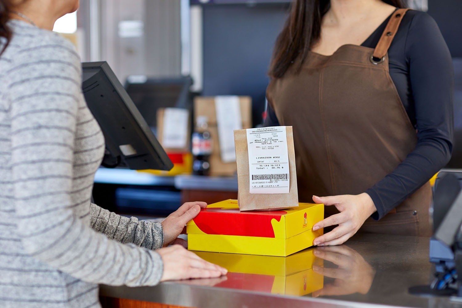 Client recevant sa commande au comptoir pour emporter d'un restaurant St-Hubert